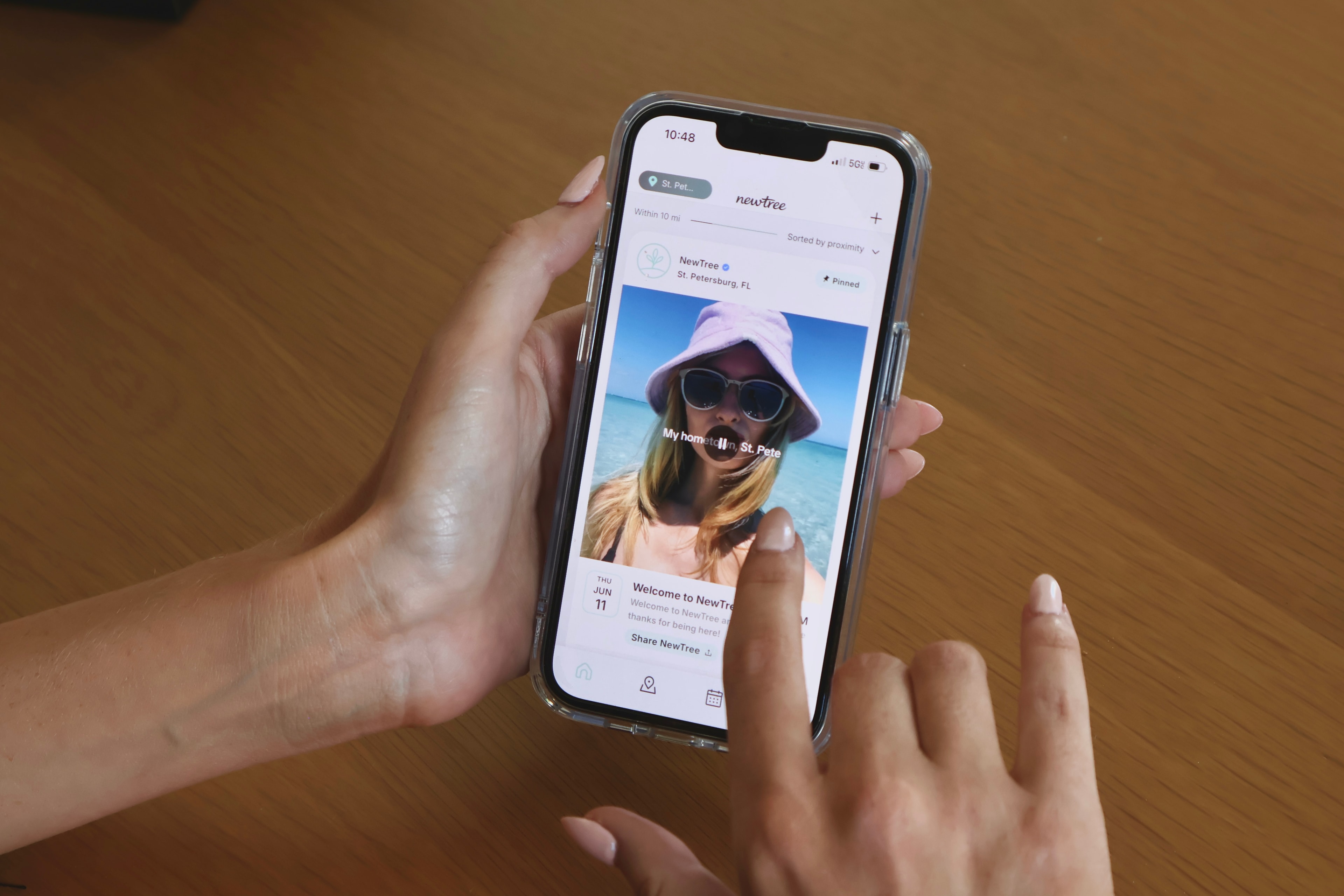 Two hands scrolling an event post in the NewTree app